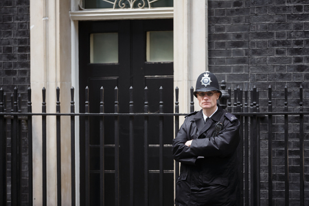 LONDON, UK - Apr 19, 2017: Metropolitan police officer on duty at 10 Downing Street official residence of First Lord of the Treasury, headquarters of Her Majesty's Government, office of Prime Ministerのeditorial素材