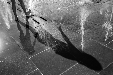 Happy children playing in a water fountain in a hot day. Close-up of girls legs in a fountainの写真素材