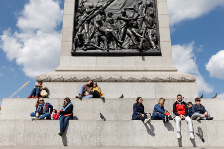 LONDON, UK - Apr 19, 2017: Adults and children rest at the base of the Nelson column. Nelson Column is a monument in Trafalgar Square in central London built to commemorate Admiral Horatio Nelsonのeditorial素材