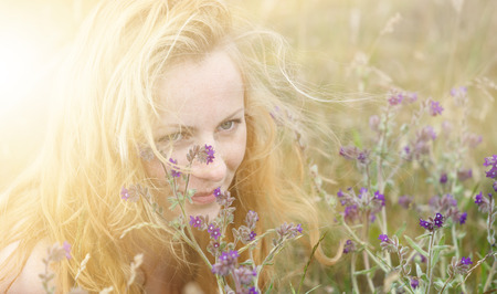 Artistic portrait of freckled woman on natural background. Young woman enjoying nature among the flowers and grass. Close up summer portraitの写真素材