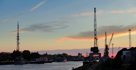 LIEPAJA, LATVIA - JUN 25, 2017: Liepaja seaport. Fishing boat moored in the harbour in Liepaja. Cranes on backgroundのeditorial素材