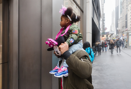 NEW YORK, USA - May 03, 2016: Madison avenue in NYC. Manhattan street scene. A dark-skinned girl sits on the shoulders of her dadのeditorial素材