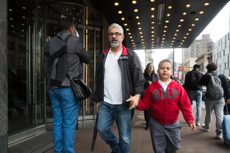 NEW YORK, USA - May 03, 2016: Manhattan street scene. An elderly man with a beard and glasses is holding a boy's hand and walking down Manhattan Street in New York City.のeditorial素材