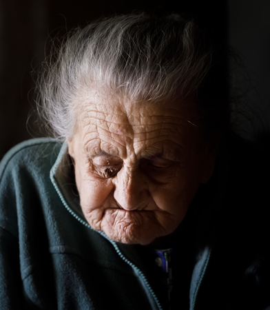 Portrait of a very old tired woman sitting near a windowの写真素材