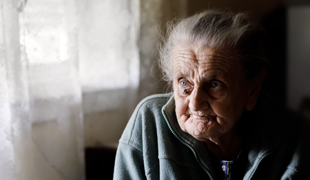 Portrait of a very old tired woman sitting near a windowの写真素材