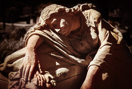 Old statue on grave in the Lychakivskyj cemetery of Lviv, Ukraine.  Intentional color shift in orange-red toneの写真素材