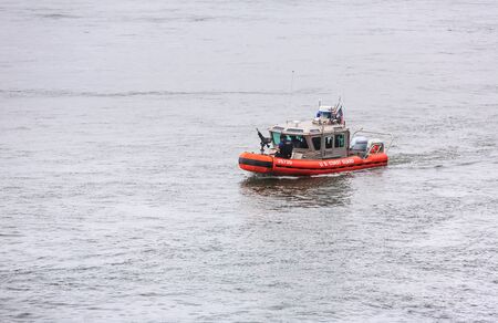 NEW YORK, USA - Sep 18, 2017: US Coast Guard patrol boat with officer manning gun on the bow patrolling East River during the 72th session of the UN General Assembly in New York Cityのeditorial素材