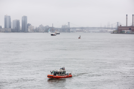 NEW YORK, USA - Sep 18, 2017: US Coast Guard patrol boat with officer manning gun on the bow patrolling East River during the 72th session of the UN General Assembly in New York Cityのeditorial素材