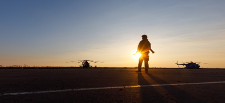 MARIUPOL, UKRAINE - Nov. 16, 2017: Silhouette of a military man with a machine gun in a combat post against the helicopters and sunset sky during festivities on occasion of the Day of Naval Infantryのeditorial素材