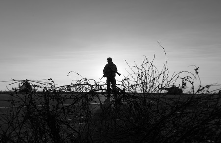 MARIUPOL, UKRAINE - Nov. 16, 2017: Silhouette of a military man with a machine gun in a combat post against the helicopters and sunset sky during festivities on occasion of the Day of Naval Infantryのeditorial素材