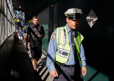 NEW YORK, USA - Sep 17, 2017: Manhattan street scene. NYC police officer walking on sidewalk with a protective fence near construction worksのeditorial素材