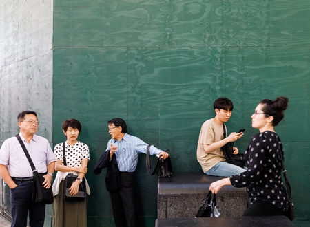 NEW YORK, USA - Sep 17, 2017: Manhattan street scene. Americans and tourists walk and relax on Times Square. A group of people are resting near a green fenceのeditorial素材