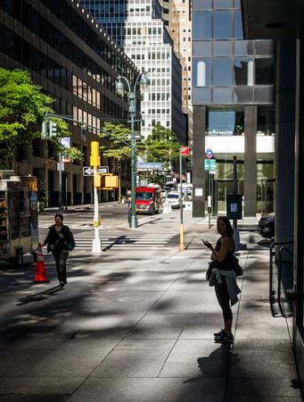 NEW YORK, USA - Sep 23, 2017: Manhattan street scene. Light and shadows on Lexington Ave in NYC. Silhouette of a lonely young woman in the sun reflected from skyscrapersのeditorial素材