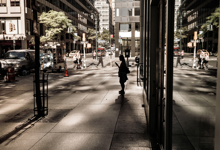 NEW YORK, USA - Sep 23, 2017: Manhattan street scene. Light and shadows on Lexington Ave in NYC. Silhouette of a lonely young woman in the sun reflected from skyscrapersのeditorial素材