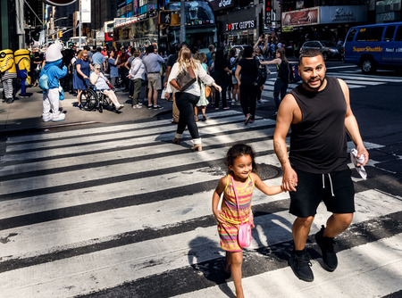 NEW YORK, USA - Sep 23, 2017: Manhattan street scene. New Yorkers and tourists in a hurry about their business, walking on Times Square. Young father with his daughter on pedestrian crossingのeditorial素材