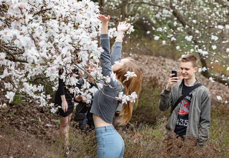 KYIV, UKRAINE - Apr 17, 2018: People enjoy magnolia blossoms. People photograph and making selfies in blossoming magnolia garden. Blossoming magnolia trees attract thousands of visitors every springのeditorial素材