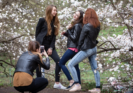 KYIV, UKRAINE - Apr 17, 2018: People enjoy magnolia blossoms. People photograph and making selfies in blossoming magnolia garden. Blossoming magnolia trees attract thousands of visitors every springのeditorial素材