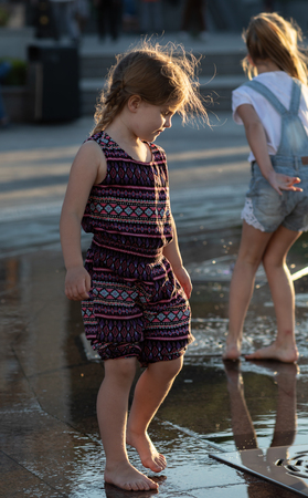 KIEV, UKRAINE - Jun 05, 2018: Cheerful and happy girl playing in a water fountain and enjoying the cool streams of water in a hot day. Hot summer.のeditorial素材