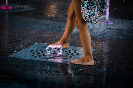 KIEV, UKRAINE - Jun 05, 2018: Cheerful and happy girl playing in a water fountain and enjoying the cool streams of water in a hot day. Hot summer.のeditorial素材