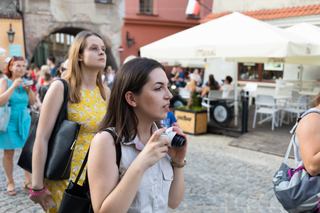 Lublin, Poland - Jul 27, 2018: Crowds of tourists and holidaymakers on the streets of the old city of Lublin. Young woman with camera. Lublin is the ninth largest city in Polandのeditorial素材