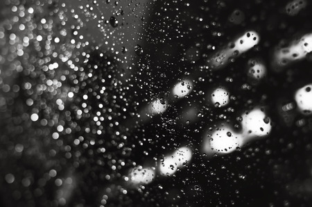Blurred New York City street background with waterdrops, neon lights and cars at raining evening...