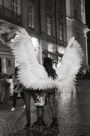 Lviv, Ukraine - Oct 13, 2018: Young girl with angel wings and roller skates on the streets of Lviv at nightのeditorial素材