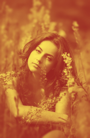 Duotone yellow and red image of young woman with wild flowers on backgroundの写真素材