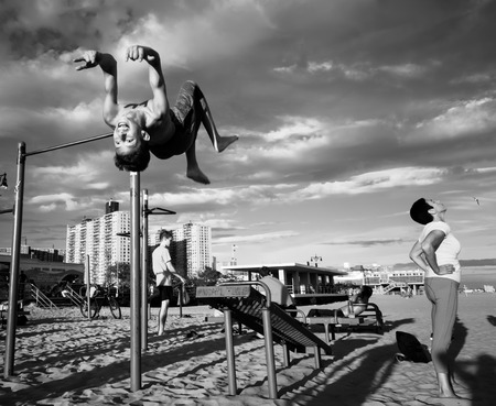 NEW YORK, USA - Sep 22, 2017: Black and white image of Coney Island Beach in New York City. A group of young people doing sports exercises on a sandy beachのeditorial素材