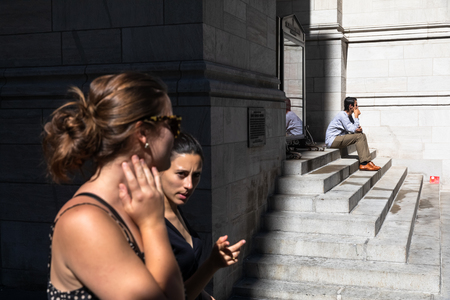 NEW YORK, USA - Sep 23, 2017: Manhattan street scene. Man is sitting on the steps of Saint Thomas Church Fifth Avenue. New Yorkers and tourists in a hurry about their business, walking on Fifth Avenueのeditorial素材