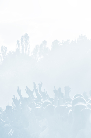 Crowd of spectators at a concert in light blue tonality. High key background with a people on an...