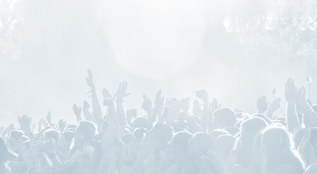 Crowd of spectators at a concert in light blue tonality. High key background with a people on an...