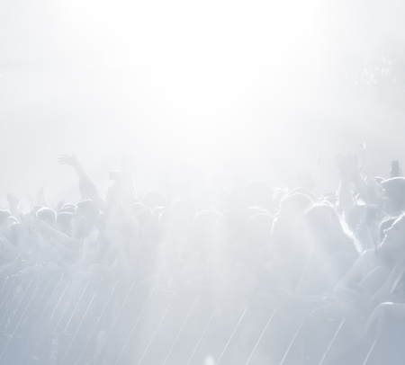 Crowd of spectators at a concert in light blue tonality. High key background with a people on an open playground at a concert. Abstract soft focus image with copy spaceの写真素材