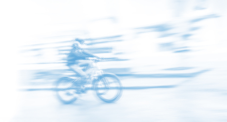 Cyclist on the city roadway in motion blur. Image in light blue tonalityの写真素材