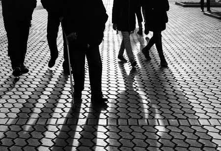 Life style concept. Light and shadows in city. Silhouettes of people walking the streets of a big city and lit by back light. Shadows of people walking street in evening light.の写真素材
