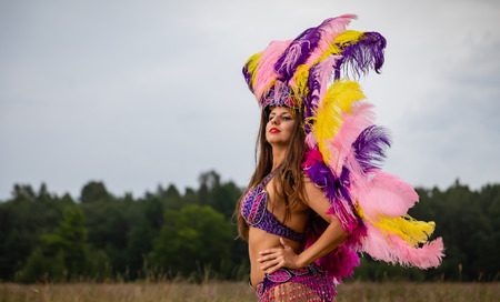 Young woman in bright colorful carnival costume posing outdoors.