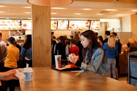 KYIV, UKRAINE - May 05, 2017: Young people have a rest and eating in a Mcdonald's in Kyiv, Ukraine. Mcdonald's is a very good place for young people.  Illustrative editorial.のeditorial素材