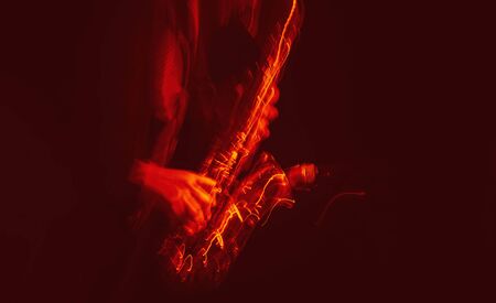 Jazz music concept. Abstract motion blurred image of saxophone player performing on stage. Sax player going crazy.の写真素材