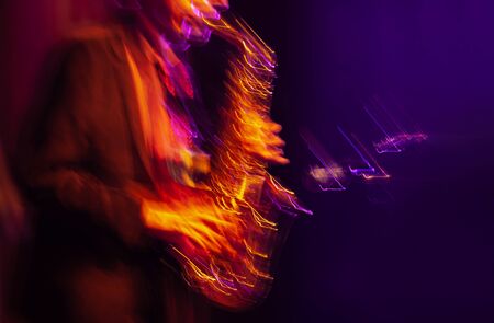 Jazz music concept. Abstract motion blurred image of saxophone player performing on stage. Sax player going crazy.の写真素材