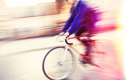 Abstract blurred image of cyclist on the city roadway. Intentional motion blur. Vintage filter with intentional color shiftの写真素材