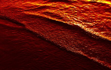 Natural background and glare on the surface of the sea. Small waves in otherwise calm water during the sunset timeの写真素材