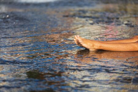 Happy children playing in a water fountain in a hot day. Close-up of children legs in a fountainの写真素材
