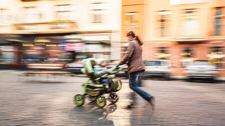 Mother with small children and a pram walking down the street. Intentional motion blurの写真素材