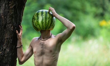 Organic food and healthy lifestyle concept. Humorous ironic photo of a boy with a watermelon instead of head on nature backgroundの写真素材