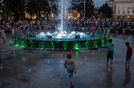 LUBLIN, POLAND - JULY 27, 2018: Happy children playing in a water fountain in Lublin at night. Lublin is the ninth largest city in Polandのeditorial素材