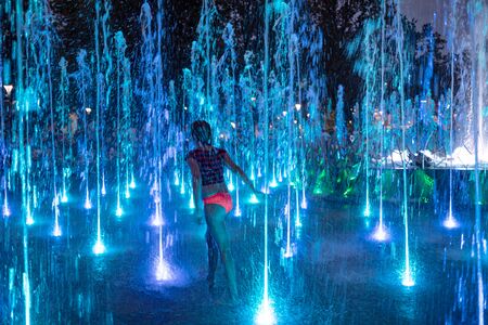 LUBLIN, POLAND - JULY 27, 2018: Happy children playing in a water fountain in Lublin at night. Lublin is the ninth largest city in Polandのeditorial素材