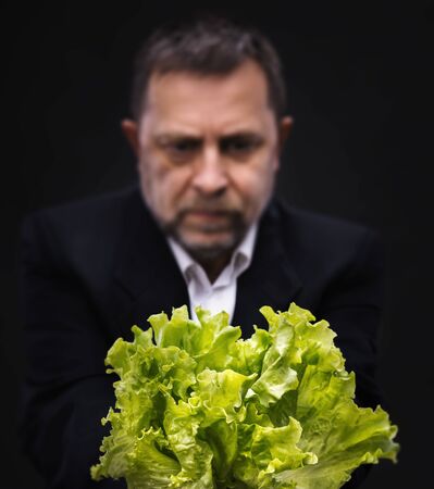 Healthy lifestyle and healthy eating concept. Man holding and eating lettuceの写真素材
