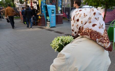 Kyiv, Ukraine - May. 03, 2017: Street scene in Kyiv, the capital of Ukraine. An elderly woman in a scarf with a bouquet of lilies of the valley on Khreshchatyk in Kyivのeditorial素材