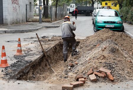 KYIV, UKRAINE - Sep 28, 2019: Worker with shovel in a trench, dig trenches along the roadのeditorial素材