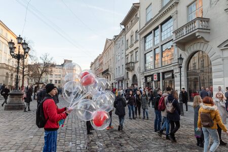 Lviv, Ukraine - Mar 08, 2019: Lviv street scene. Streets and architecture of the old Lviv city. A young man sells balloons in the square in Lvivのeditorial素材