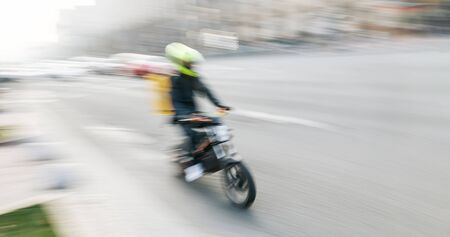 Soft focus motion blurred image of a food delivery courier delivers food. Long exposure time. Motion blur imageの写真素材